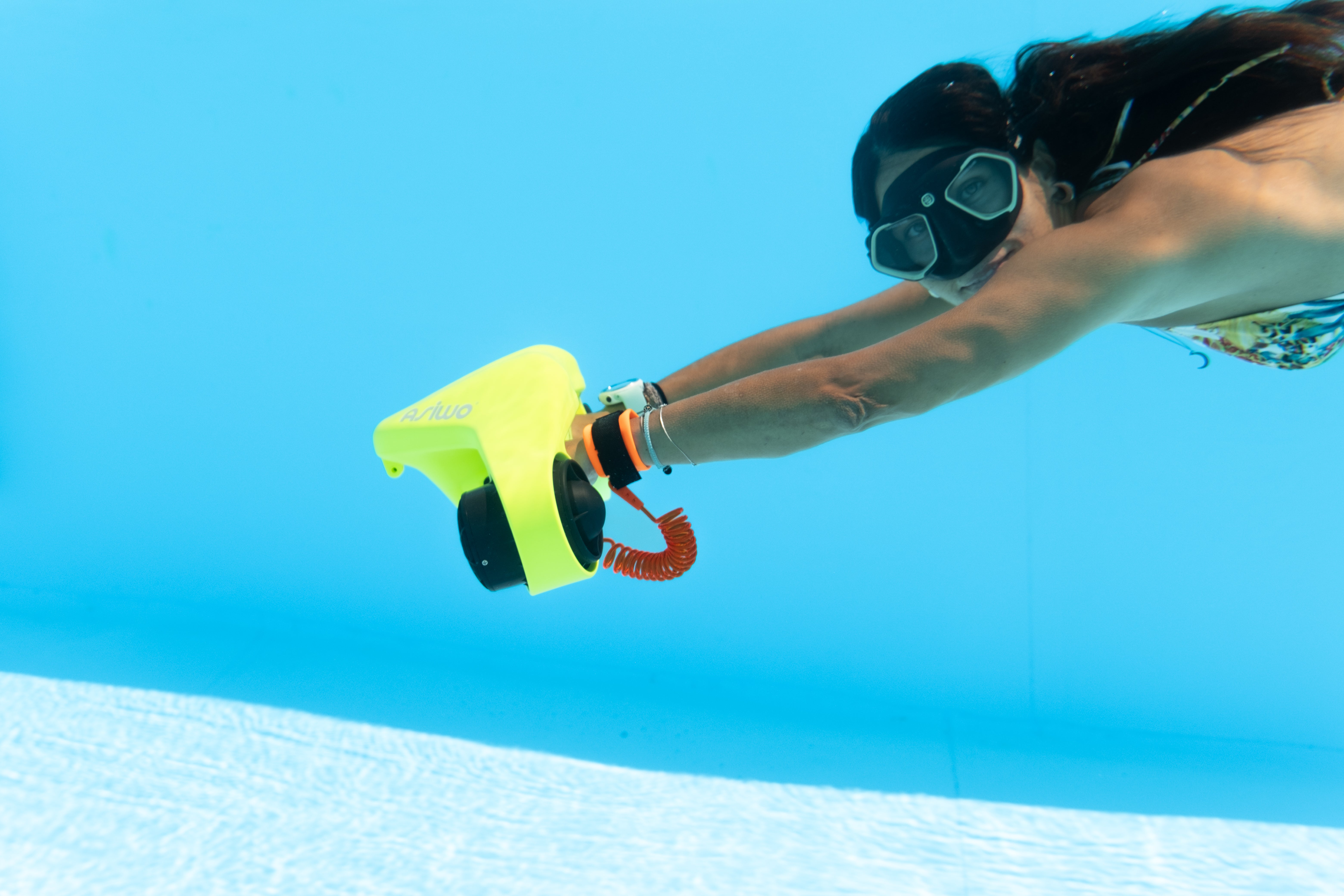 A woman swimming with a yellow underwater scooter.