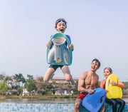 This image shows the different variants of Asiwo Mako Electric Kickboard being held by 3 people, one in the photo is jumping onto the pool holding the green Asiwo Mako Electric Kickboard while the other two holding the blue and yellow boards respectively are sitting on the edge of the pool watching the jumper.