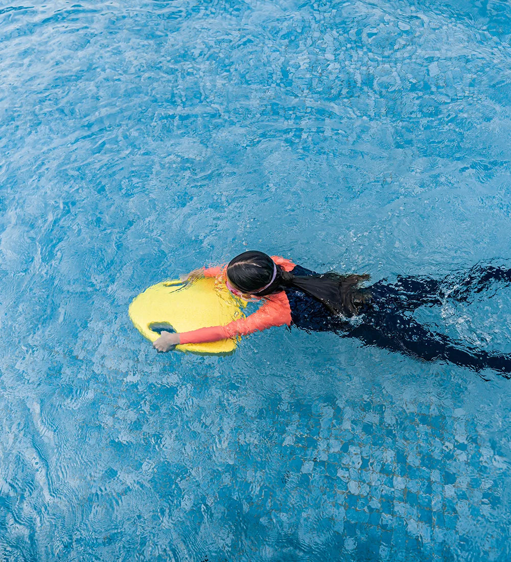 Overhead view of a person swimming in a pool using ASIWO Mako kickboard.