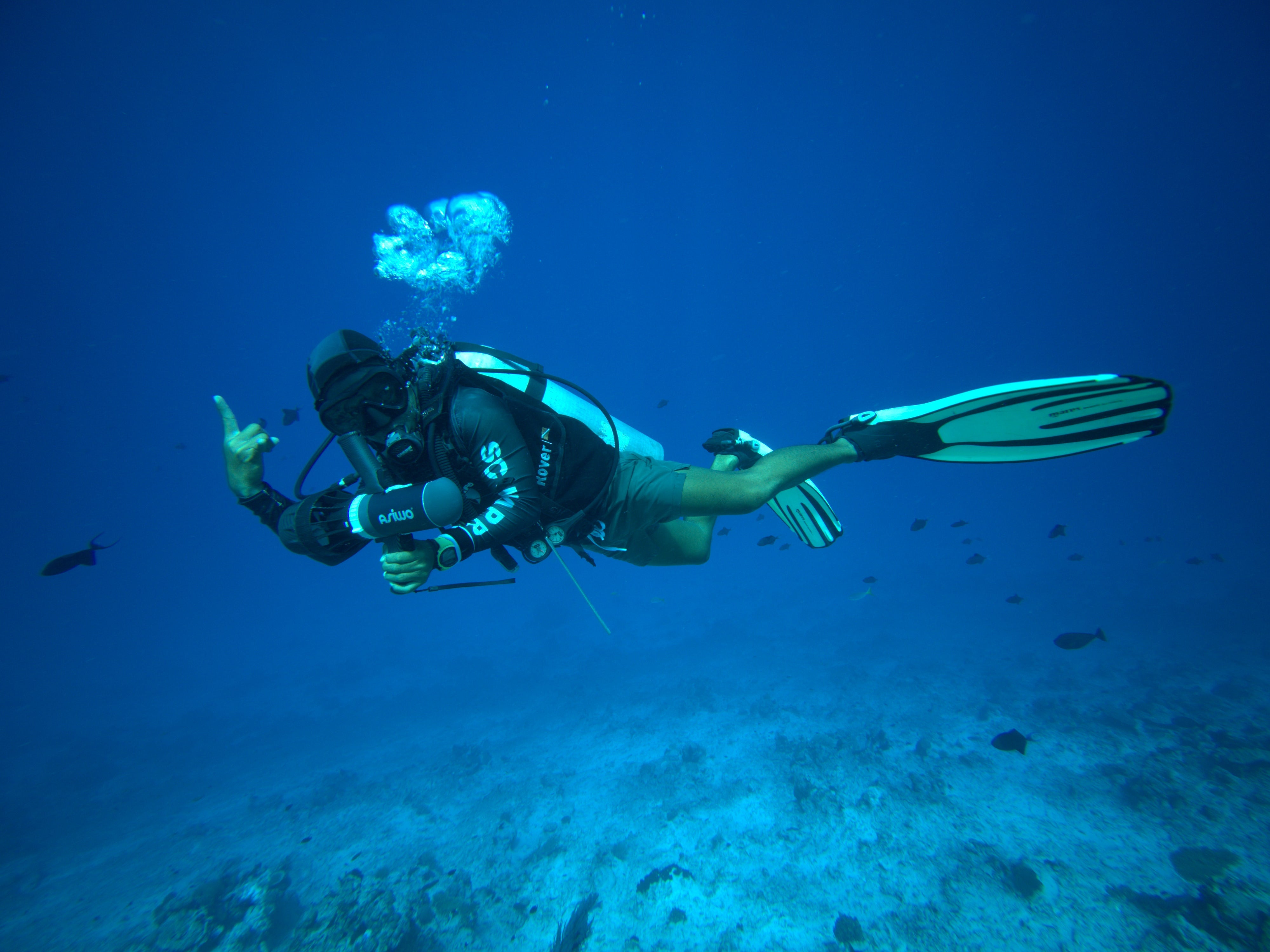 Scuba diver using ASIWO U1 Diver Propulsion Vehicle while exploring deep blue ocean.