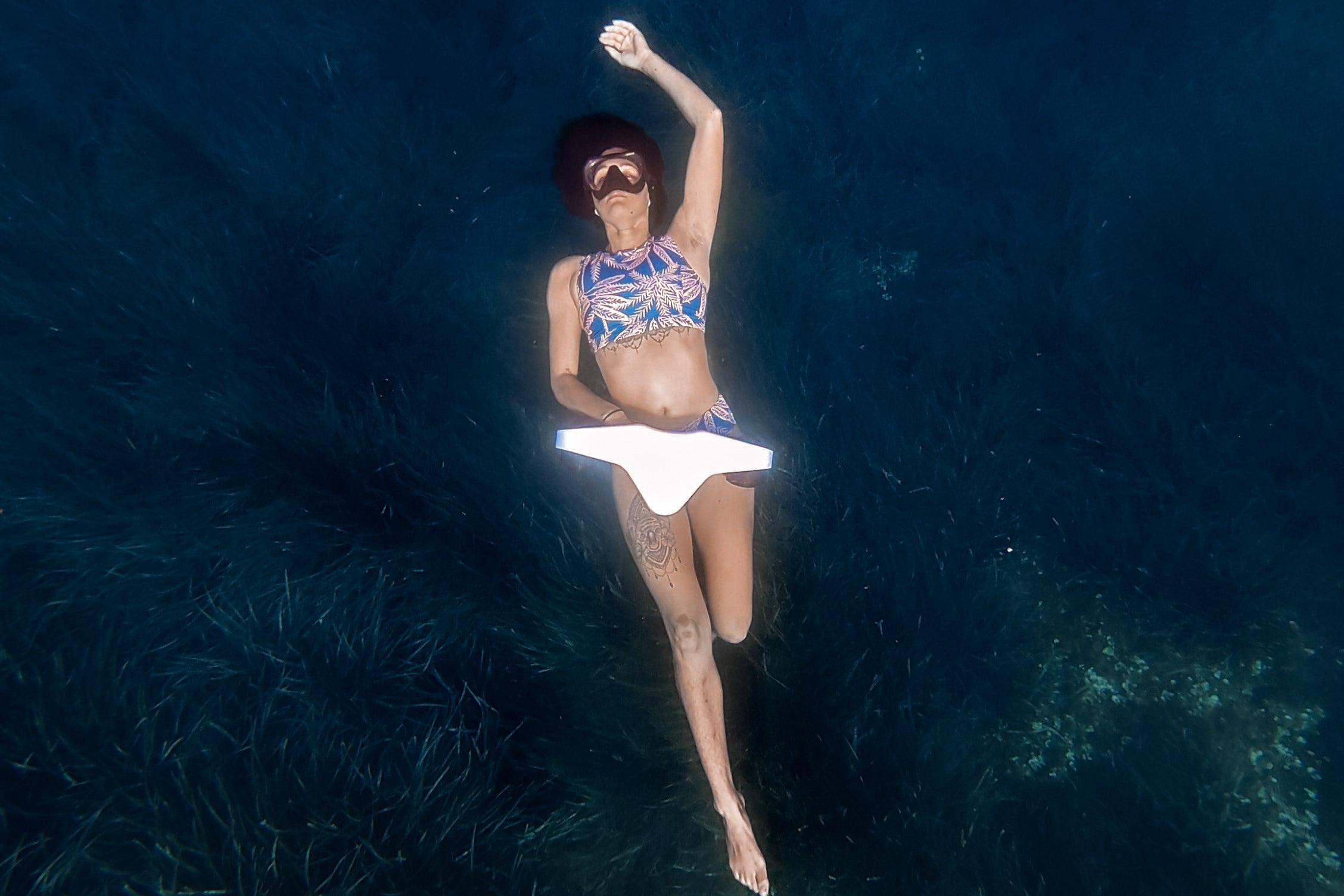 Woman snorkeling in deep blue water using a white Asiwo Manta underwater scooter from a top-down view.
