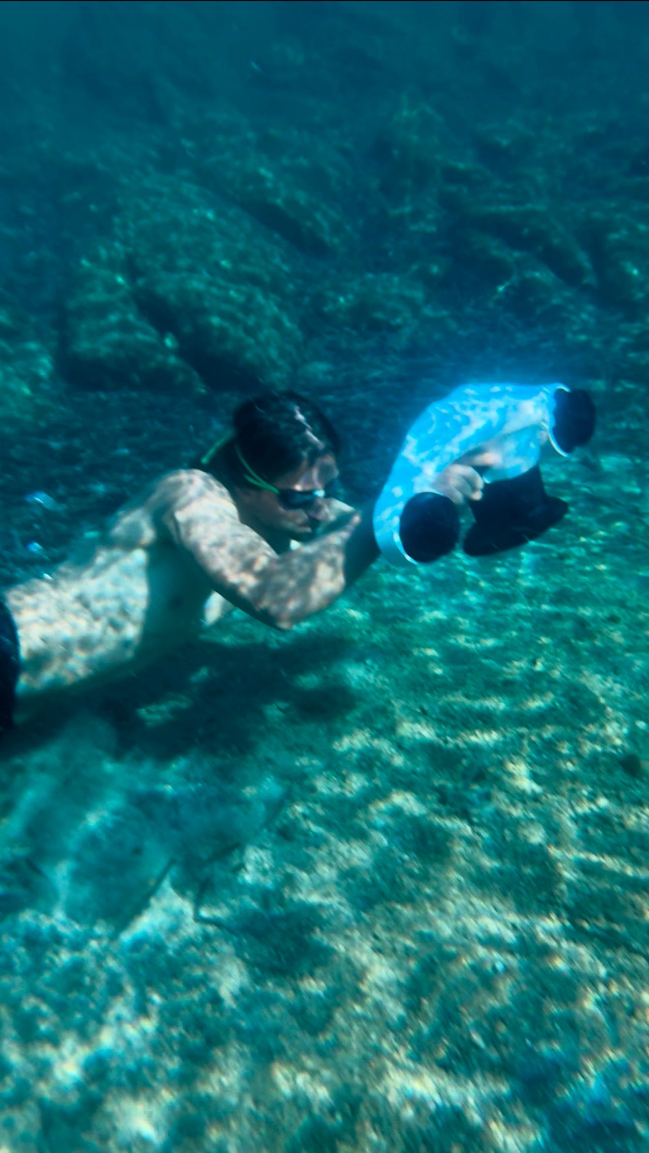 A person swimming underwater holding a blue Asiwo Manta scooter.
