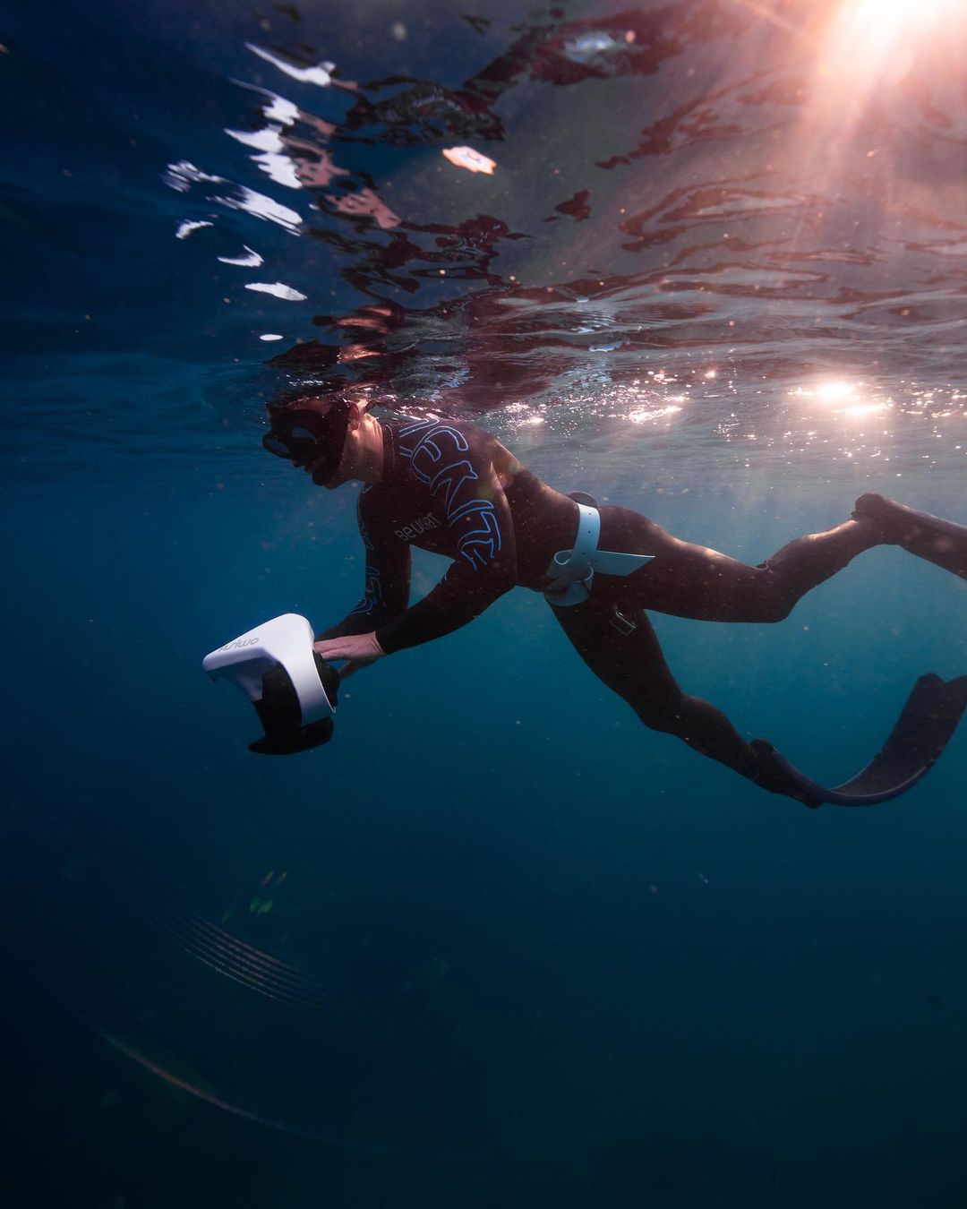  A person freediving underwater with a white Asiwo Manta scooter.