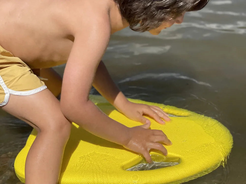 A swimmer practicing flutter kicking drills with an electric kickboard in a swimming pool