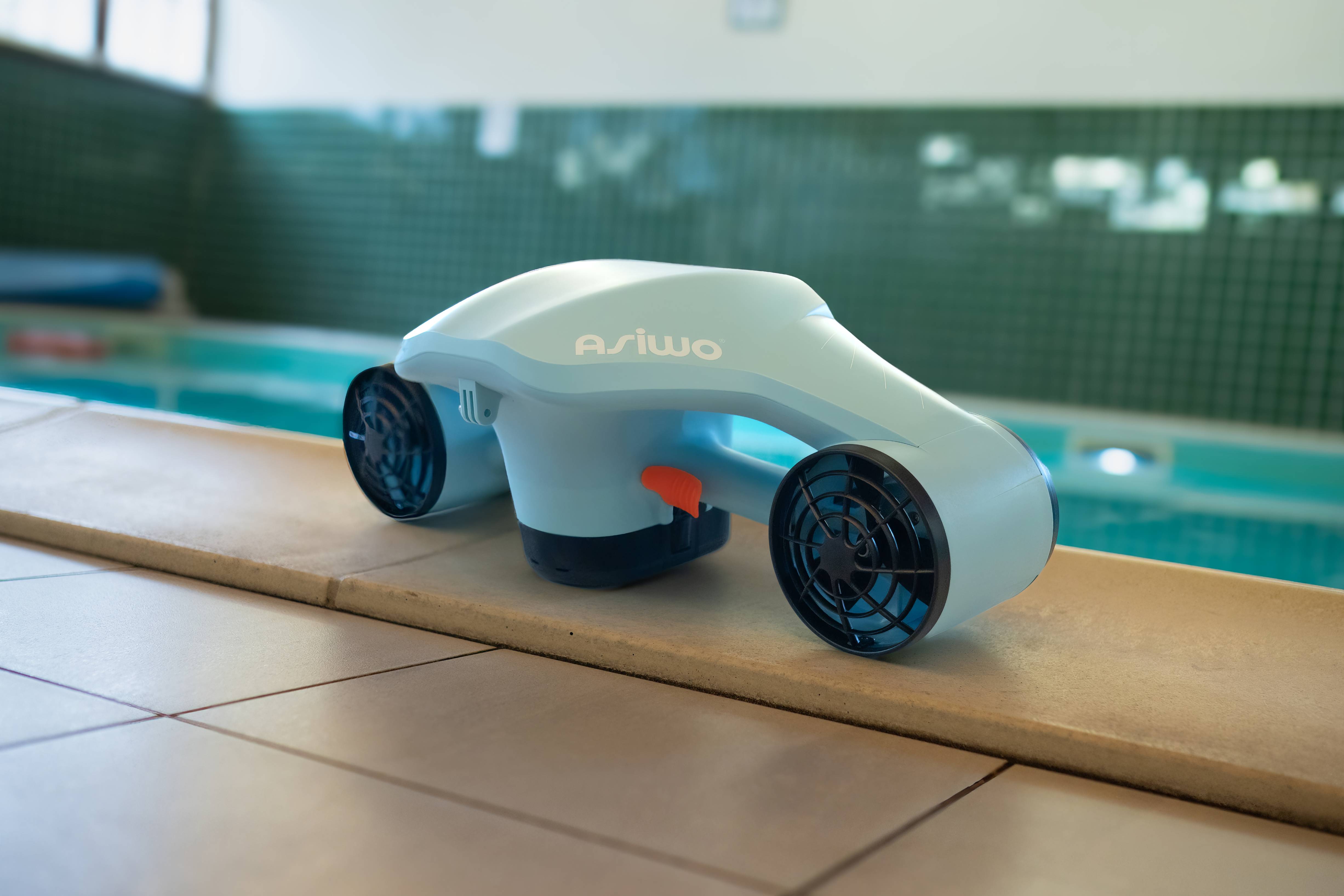 An ASIWO underwater scooter placed on the edge of an indoor swimming pool.